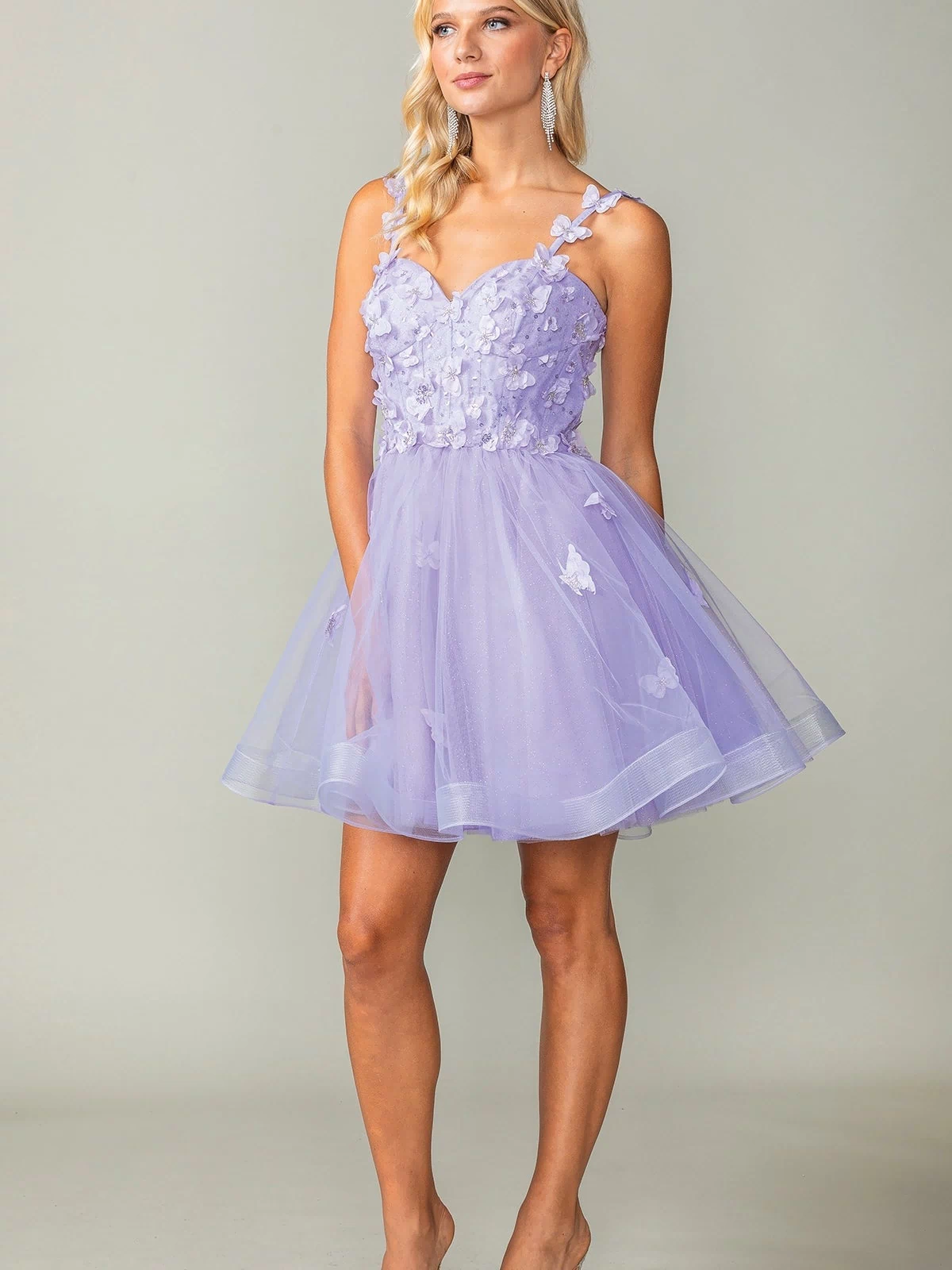 A woman in the Lace-Up Short Butterfly Homecoming Dress 3369, a light purple tulle semi-formal dress with 3-D butterflies and spaghetti straps, stands against a plain background.