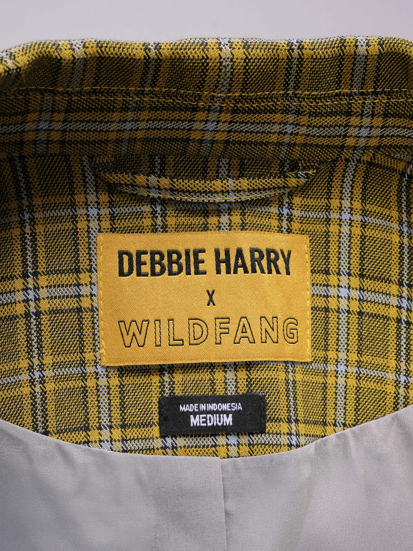 Plaid fabric with a label reading 'Debbie Harry x Wildfang' on a gray background