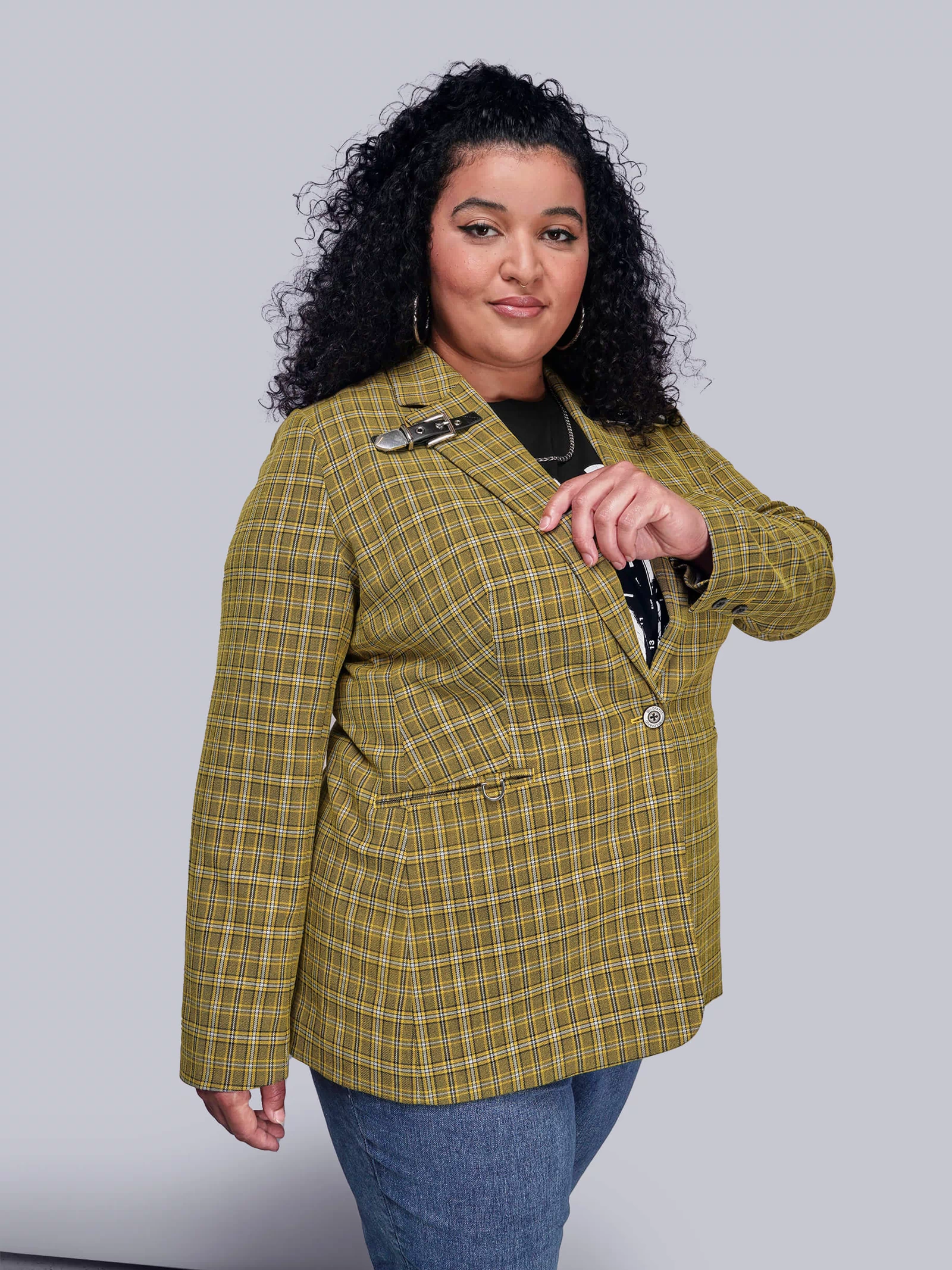 1X=Side view of person wearing a yellow plaid blazer against a gray background