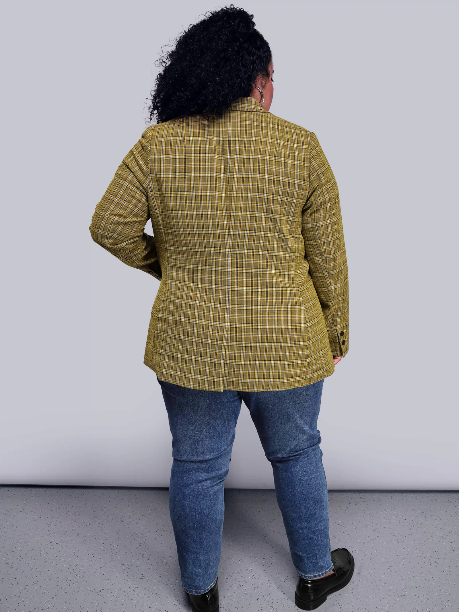 1X=Back view of person wearing a yellow plaid jacket and blue jeans against a white background