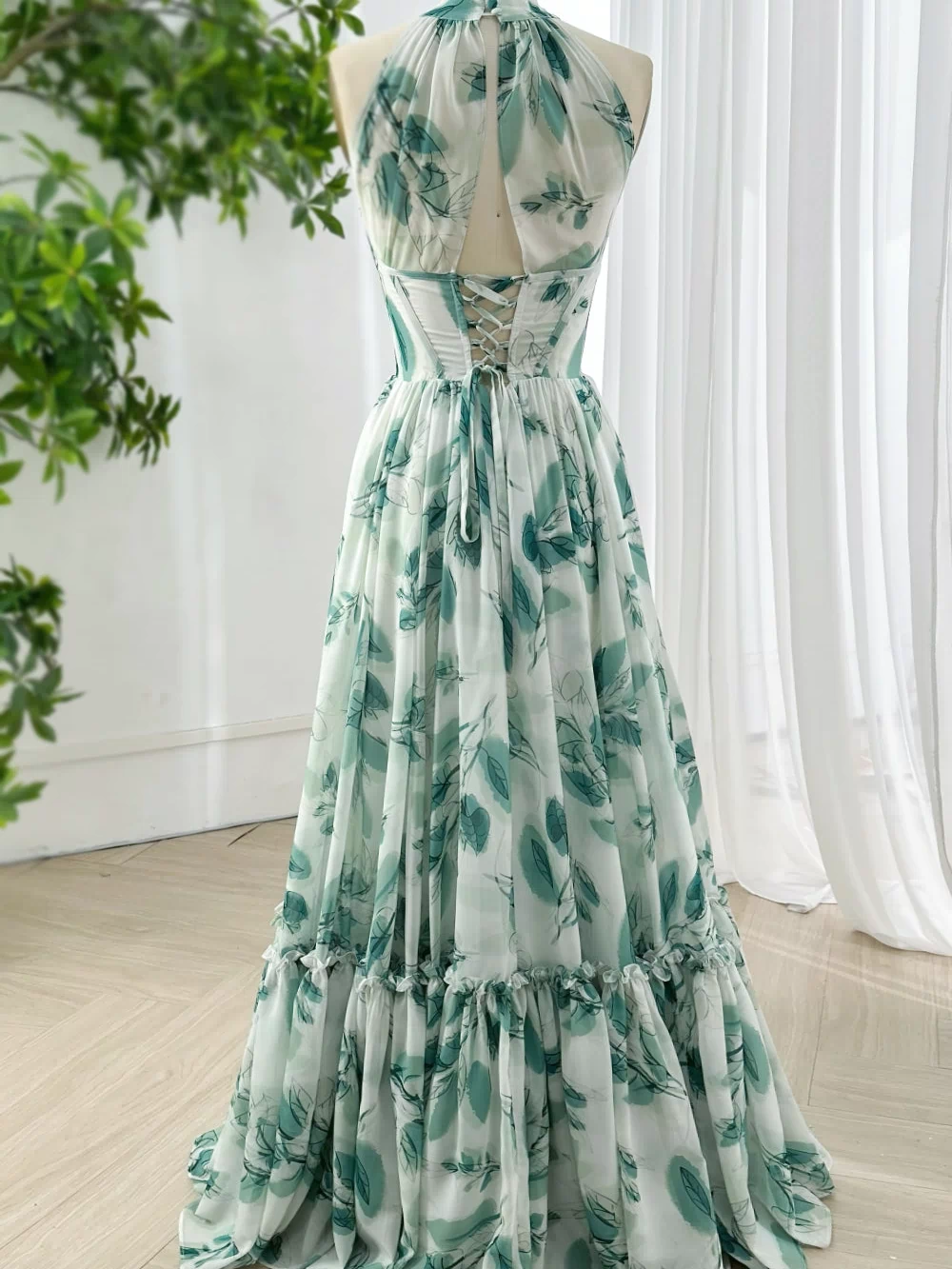 Romantic chiffon evening gown with high neck halter design and lace up open back featuring green watercolor leaves print