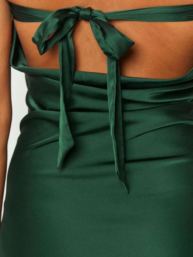 Close-up of the self-tie bow closure and draped back detail of a forest green satin mini dress