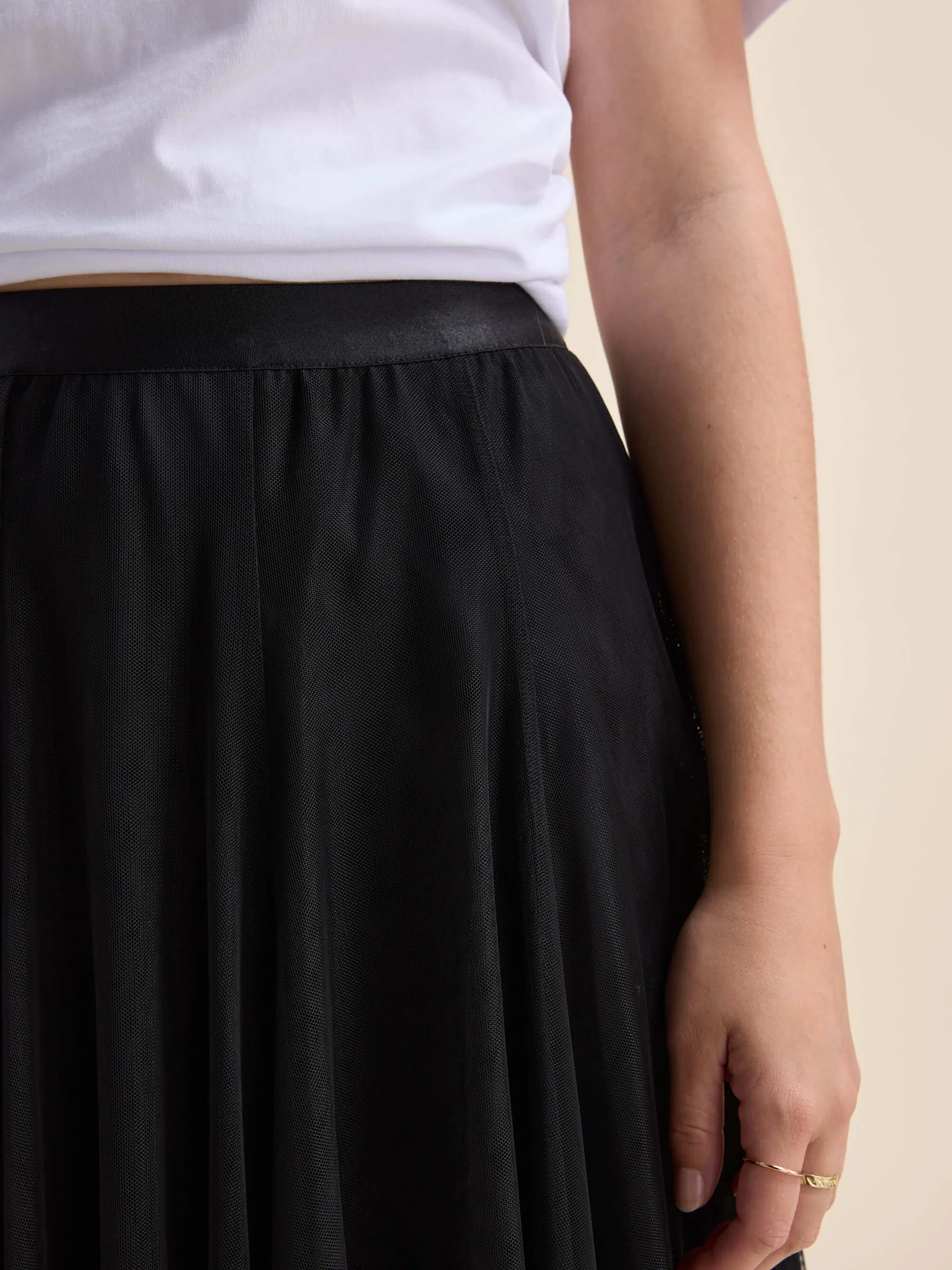 A person in a white shirt and Max Emilie Tulle Skirt stands with their arm by their side.