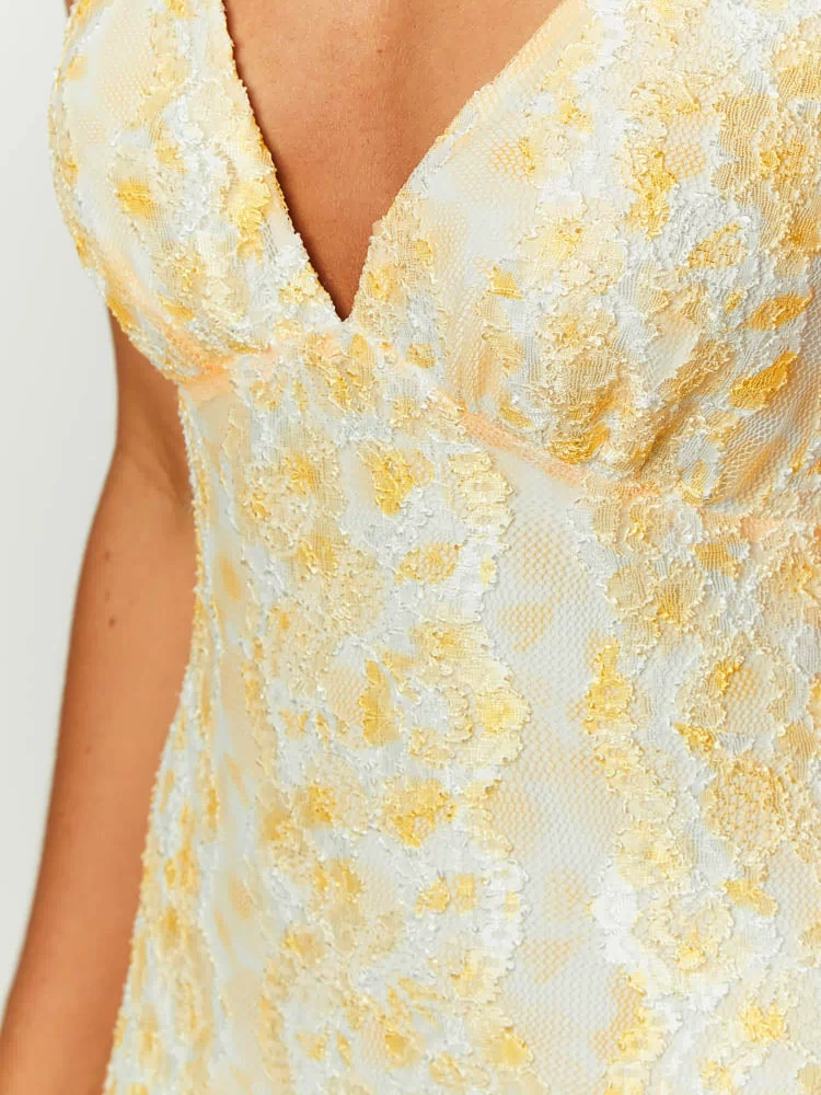 Close-up of the textured yellow and white floral lace on the V-neckline of the maxi dress