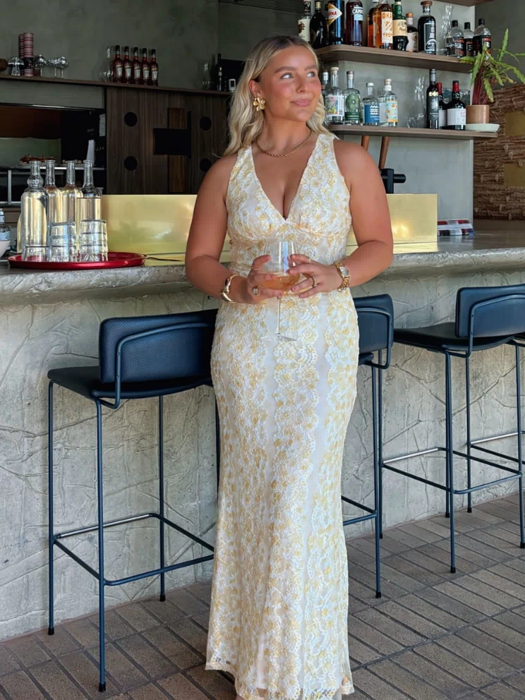 Full length view of a yellow lace maxi dress with a deep V-neck halter neckline and a fitted silhouette