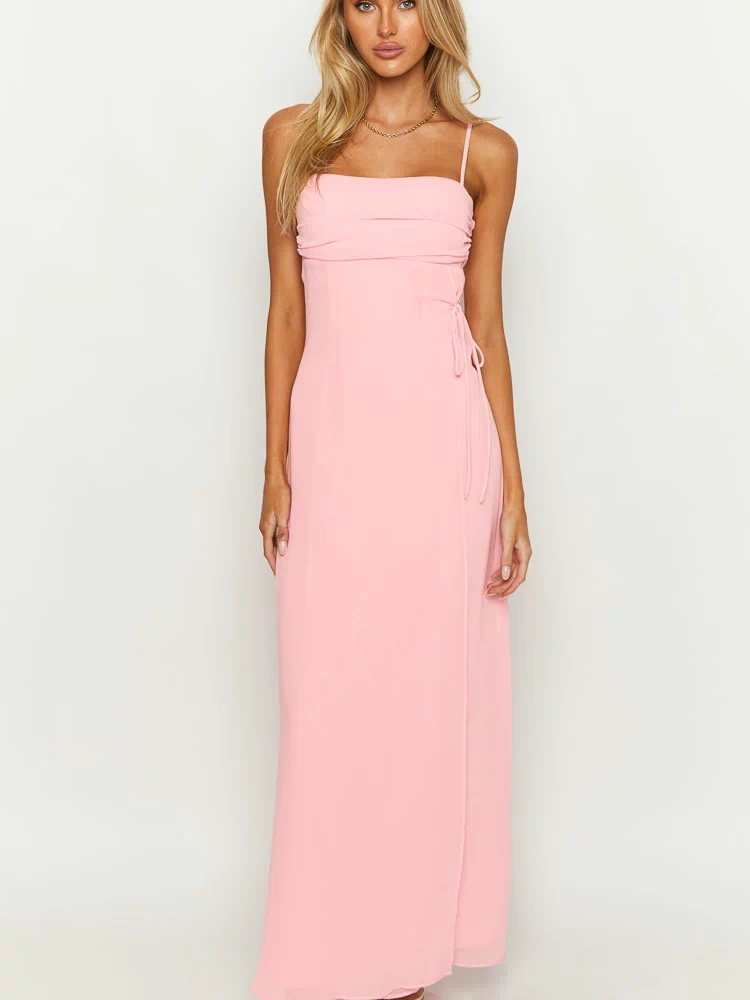 Front view of a pink maxi dress with a straight neckline, ruched bust, thin spaghetti straps, and side tie detail