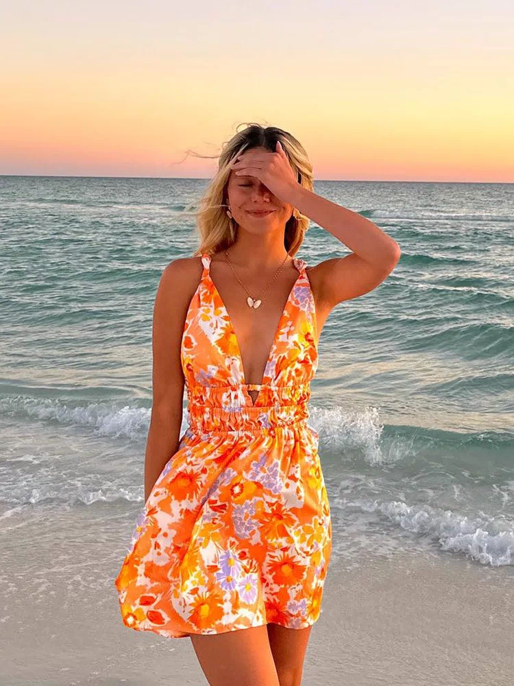 Front view of an orange floral mini dress with a deep V-neck, tied shoulder straps, and a ruched elasticated waist
