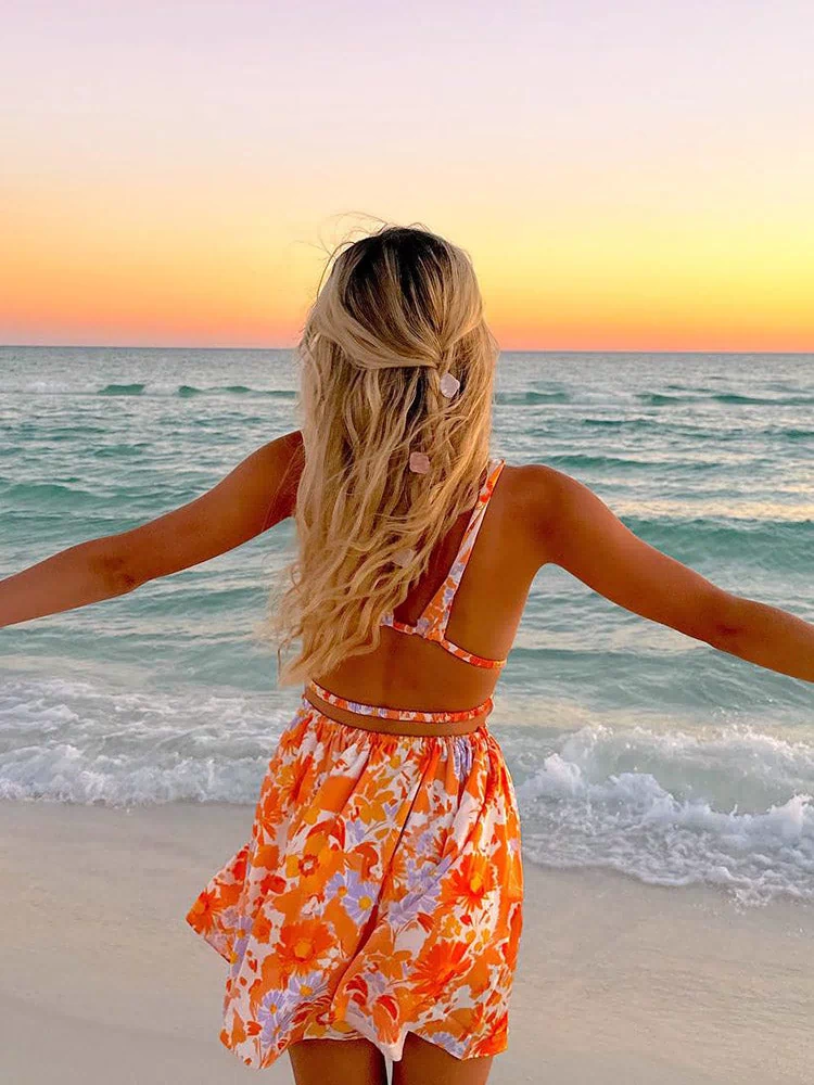 Side view of an orange floral mini dress showing the deep V-neck, side cutouts, and tie-back detail