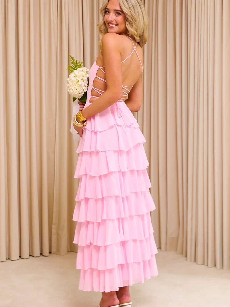 Side view of a pink ruffle maxi dress with criss-cross back straps, side cutouts, and tiered skirt