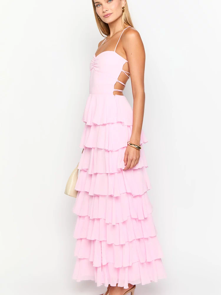 Side view of a pink tiered ruffle maxi dress with ruched bust and lace-up side cutouts