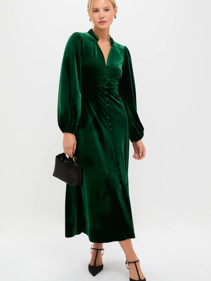 The Green Velvet Serena Dress exudes classic elegance, featuring long balloon sleeves, a fitted waist, and a front button placket, paired effortlessly with chic black heels.