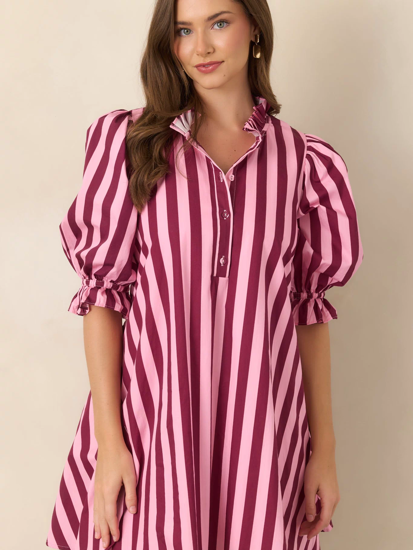 Close view of the striped cotton dress highlighting its ruffled mock collar, partial button-front placket, and softly gathered puff sleeve.