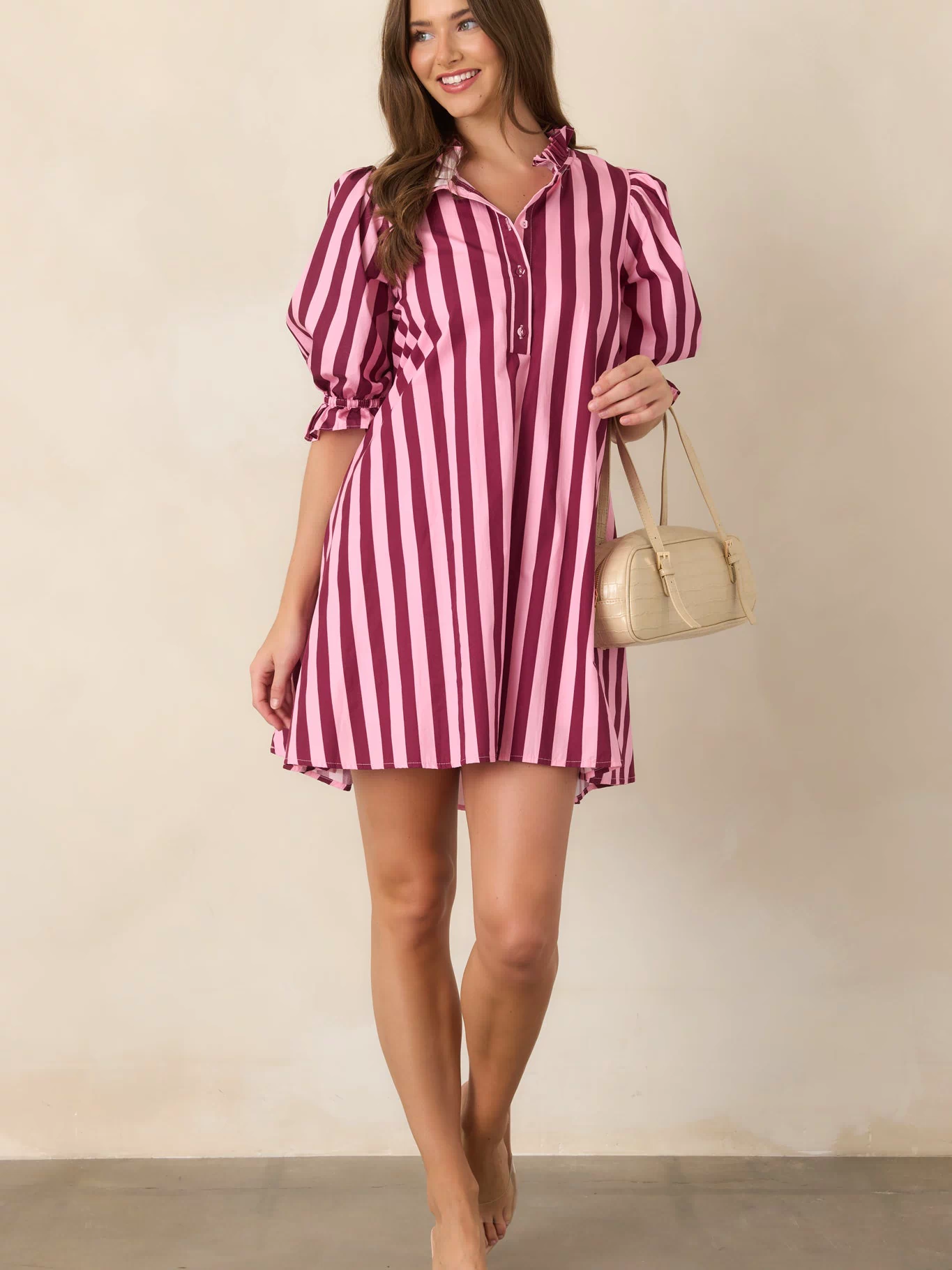 Relaxed striped mini dress designed with a ruffled mock neckline, partial button placket, generously gathered puff sleeves, and a softly shaped waist.