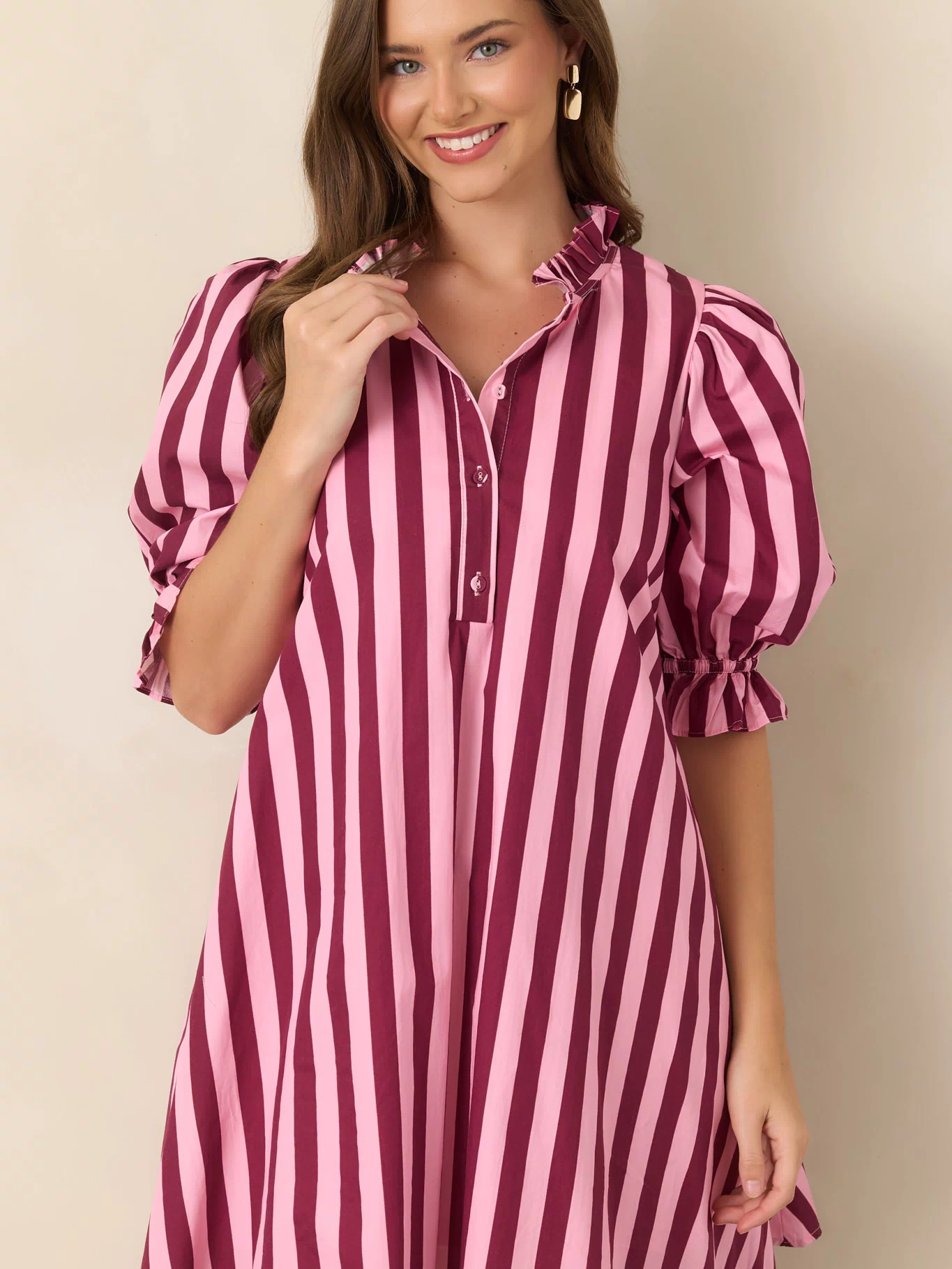 Detailed view of the pink and wine striped dress featuring its voluminous three-quarter sleeve and delicate ruffle cuff.