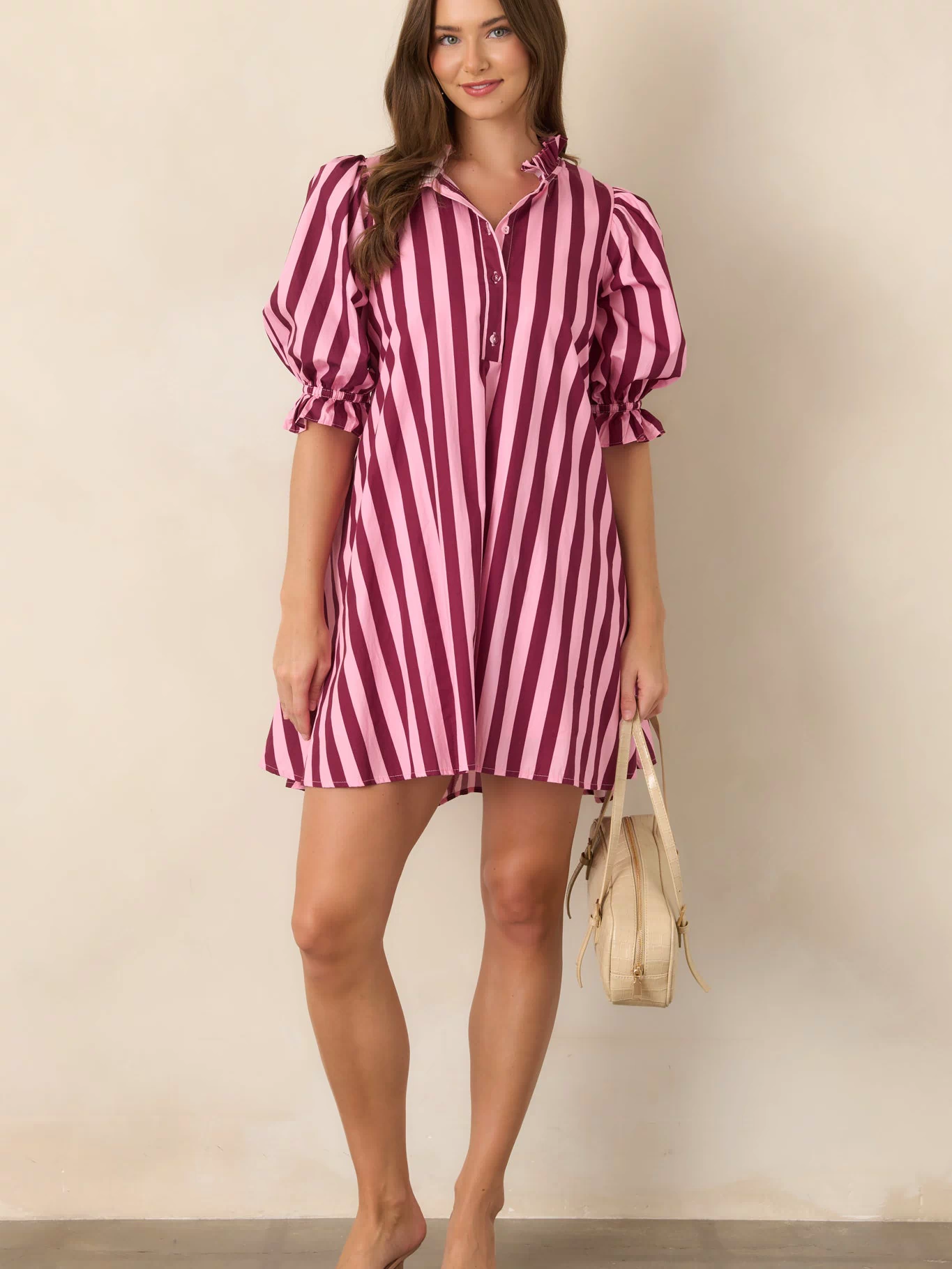 Pink and wine striped shift mini dress showcasing a softly structured cotton fabric, voluminous sleeves, ruffle-trimmed cuffs, and a subtle drawstring waist.