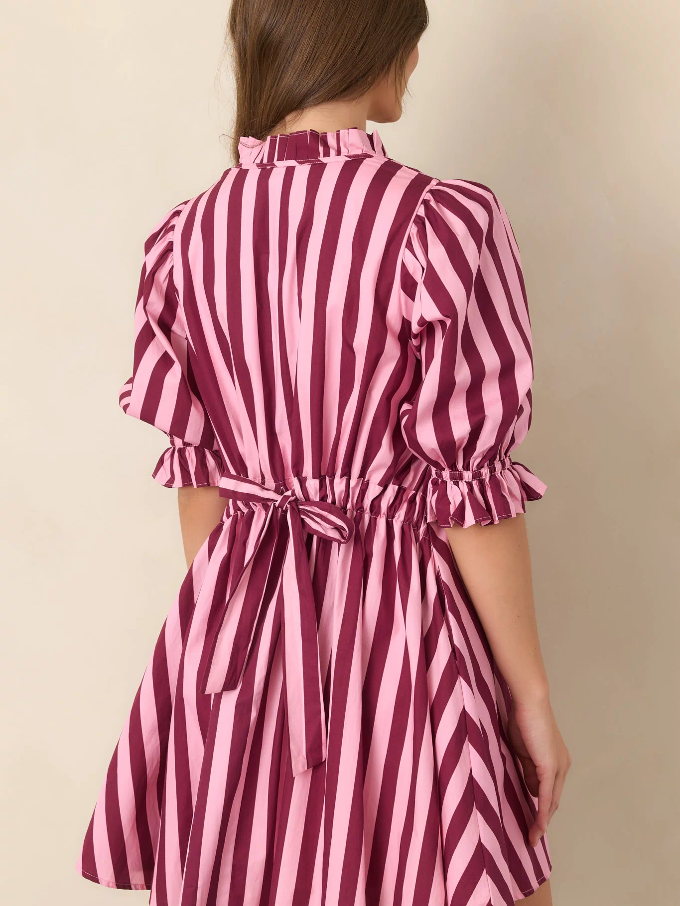 Rear view of the striped cotton mini dress showcasing the adjustable drawstring tie-back waist and relaxed shift silhouette.