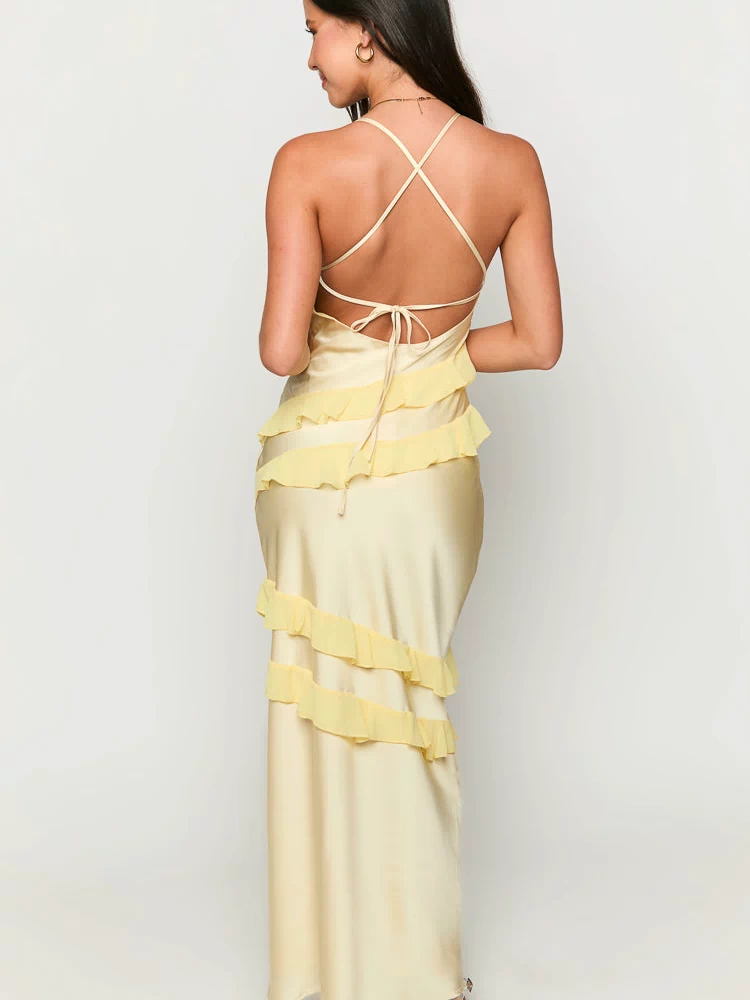 Back view of a pale yellow maxi dress with criss-cross tie-back straps and diagonal tiered ruffles