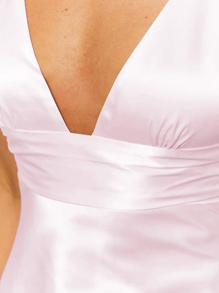 Close-up of the V-neckline and ruched bust detail on the pink satin mini dress