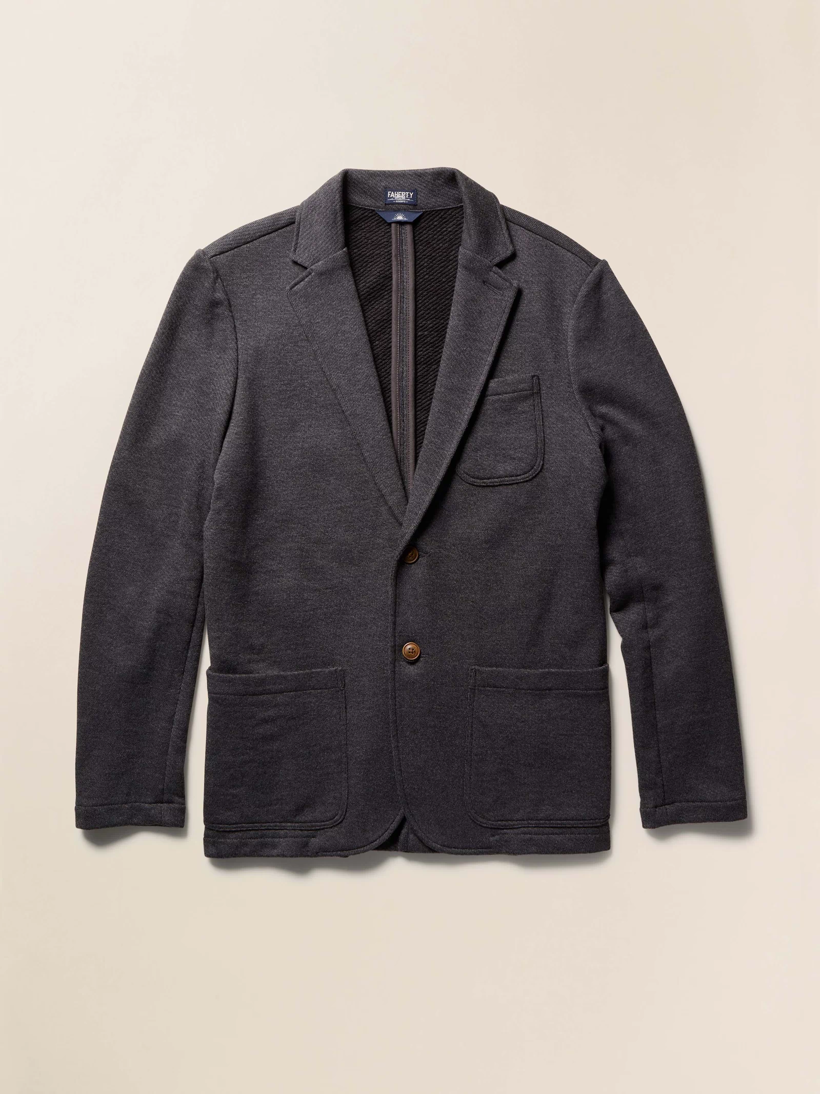 Dark gray blazer with a button on a beige background