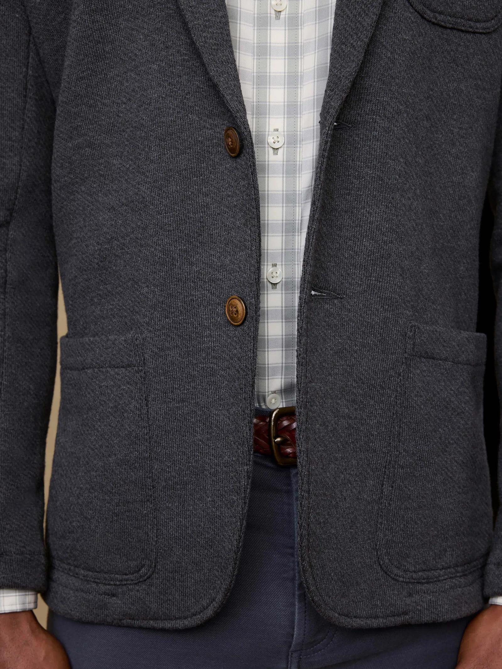 Gray blazer with brown buttons worn over a checkered shirt.