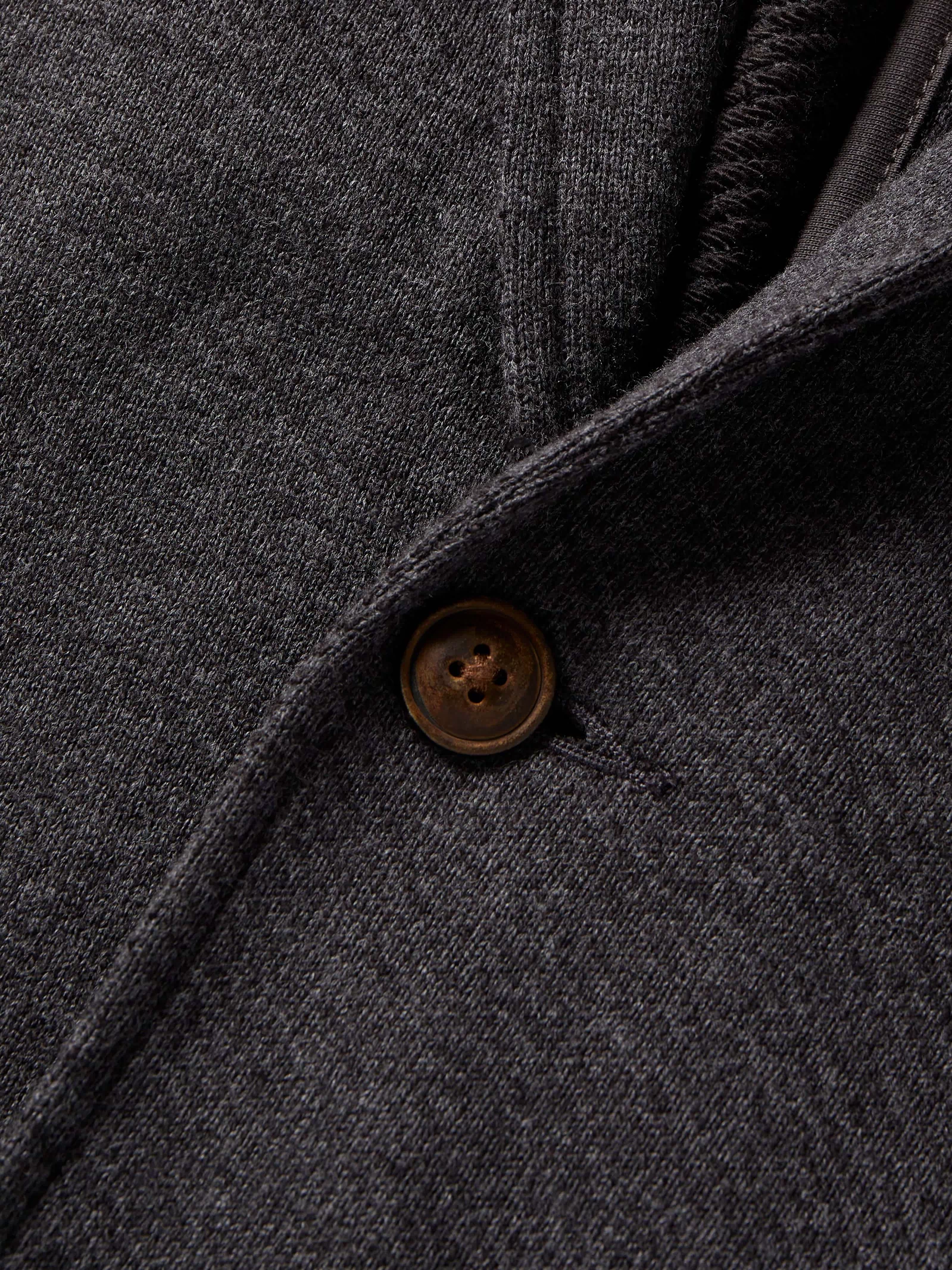 Close-up of a dark gray fabric with a button, likely from a coat or jacket.