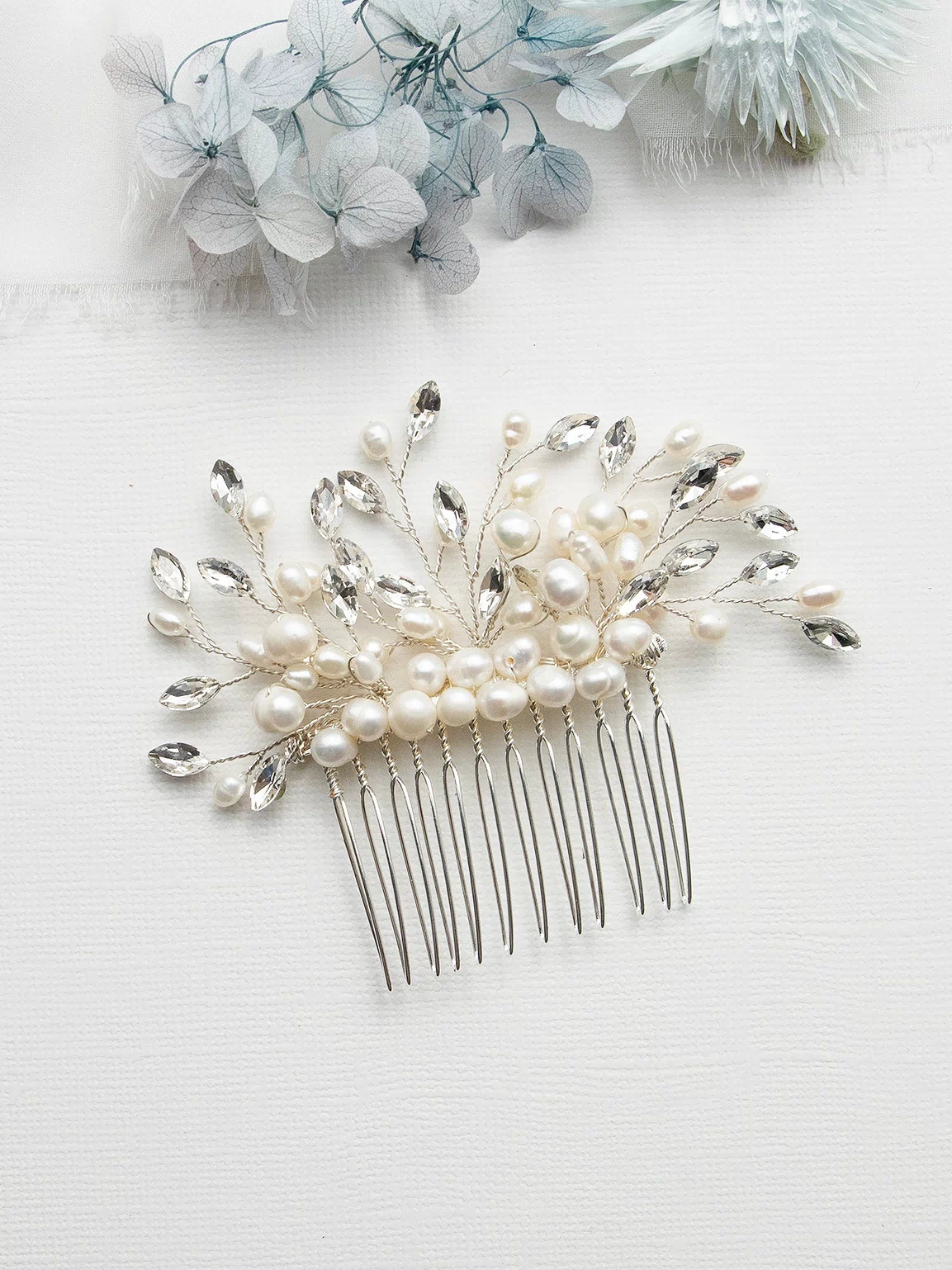 A decorative hair accessory with a comb and white pearls and crystals is displayed on a white background.