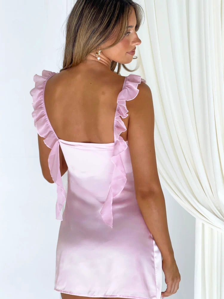 Back view of a pink satin mini dress featuring ruffled shoulder straps and a square tie-back