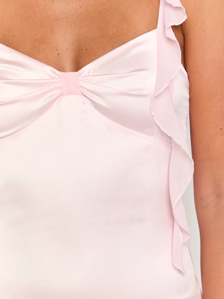 Close-up of the pink satin mini dress showing the gathered bust with a bow detail and ruffled strap