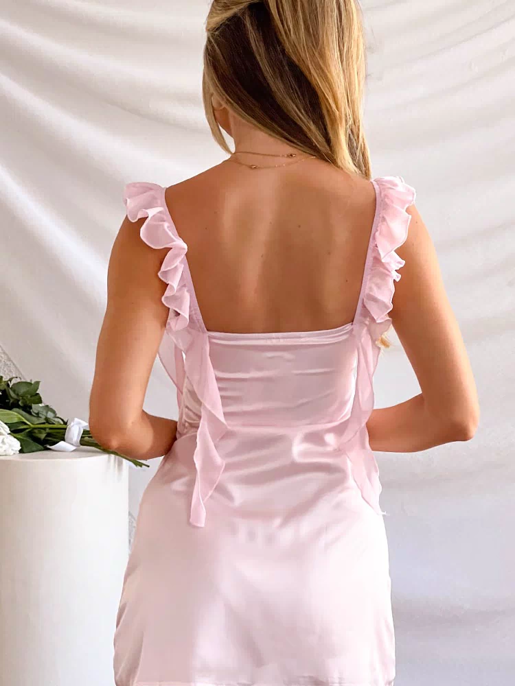 Rear view of a pink satin mini dress with a square back, ruffled shoulder straps, and sheer fabric ties