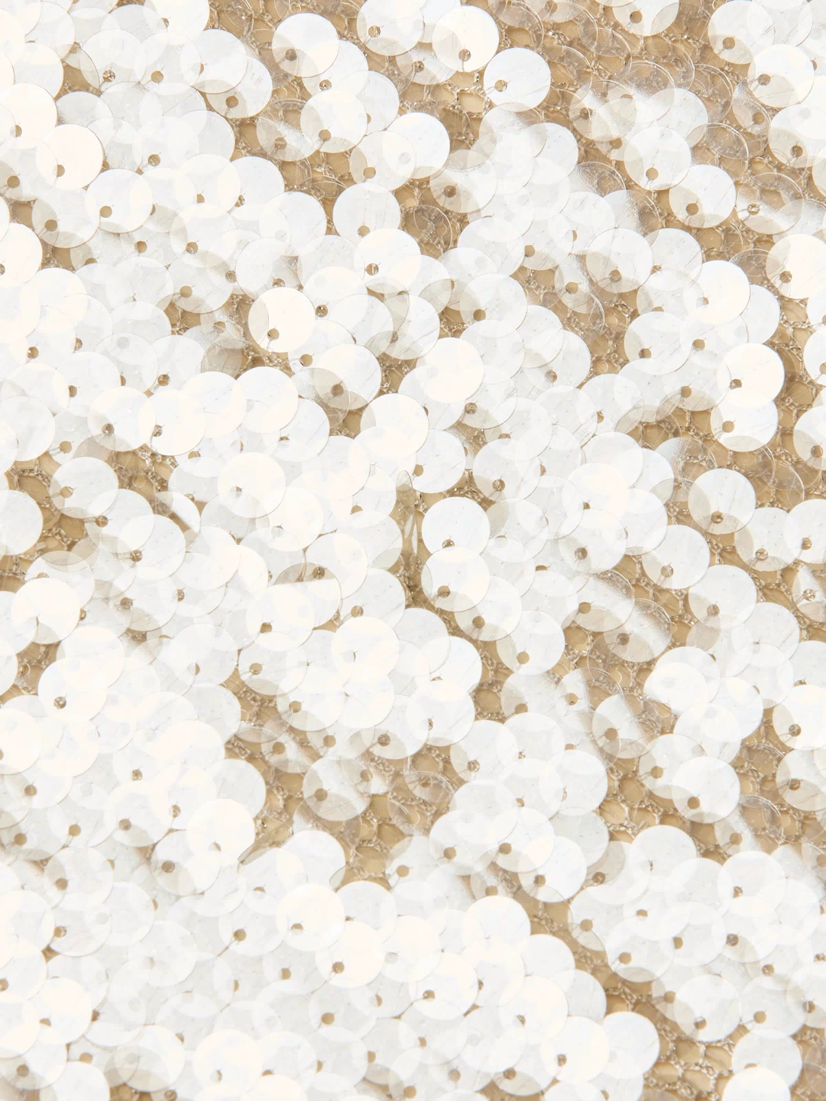 A close-up view of numerous white sequins sewn intricately onto beige fabric, creating a shimmering, textured pattern characteristic of the Karma Sequin Maxi Dress—an ideal statement piece for NYFW 2026.