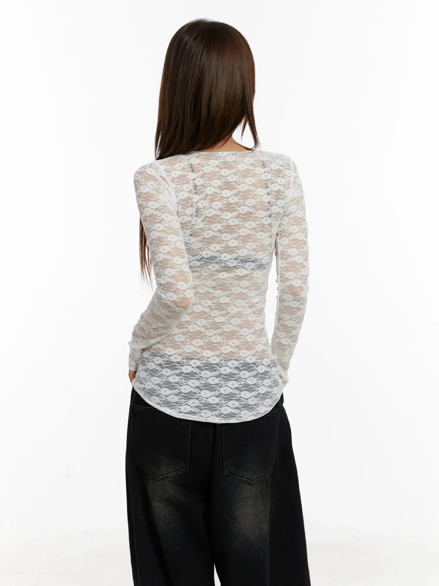 Lace Sheer Long Sleeve Top CD512 in white, back view on model, sheer floral lace showing lace hem band detail and slim silhouette, paired with black wide-leg jeans.
