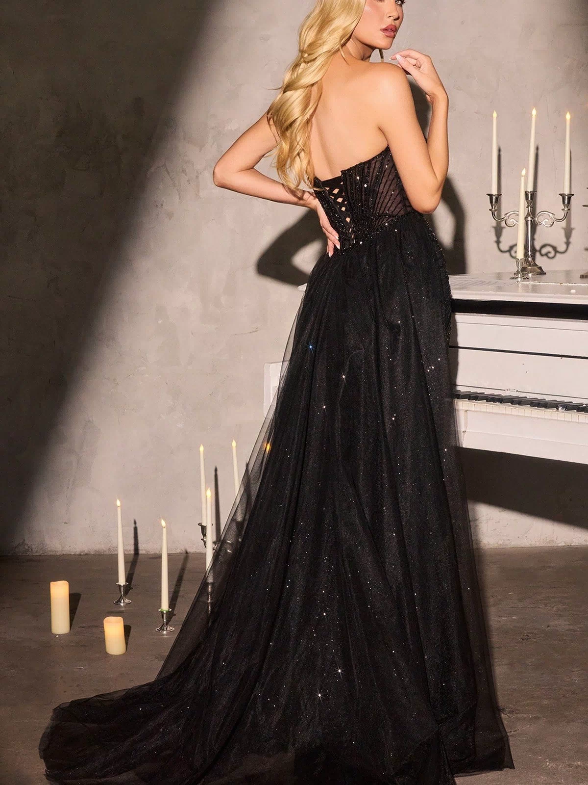 A woman with long blond hair wears the Ladivine CC492 Long Prom Dress, standing in a dimly lit room with glowing candles beside an ornate candelabra.