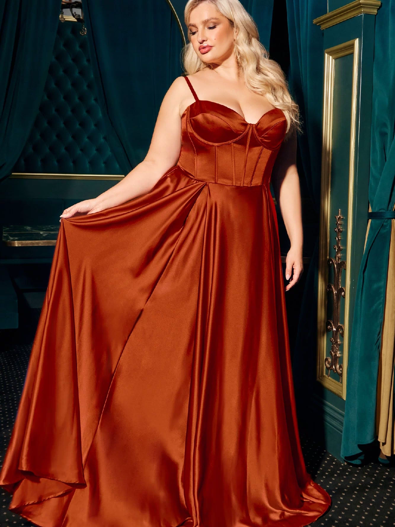 A woman in a Plus-Size Long A-Line Prom Dress, Ladivine CD337C, with a fitted bodice and flared skirt, stands indoors against a teal and gold background.