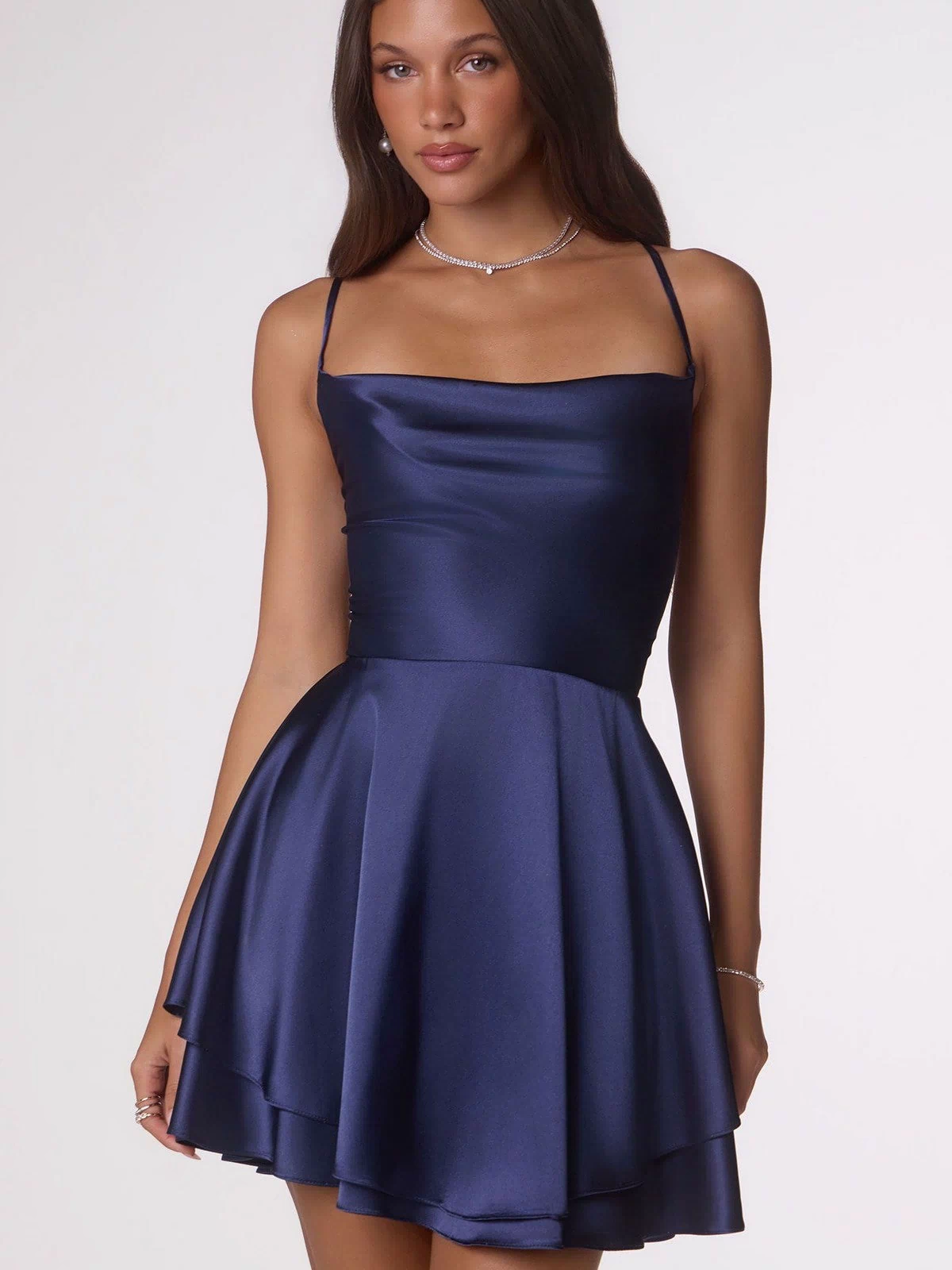 A woman wearing the Amoris T616 short navy satin homecoming dress with thin straps and an open back stands against a plain light background.