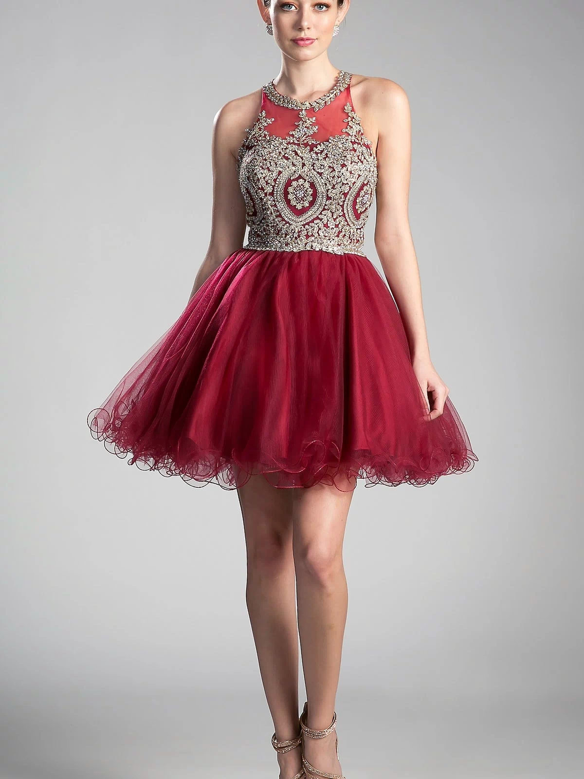 A woman models the affordable High-Neck Short Babydoll Homecoming Dress UJ0119, showcasing its beaded embroidered-lace bodice and full tulle skirt, paired with strappy heels against a simple backdrop.