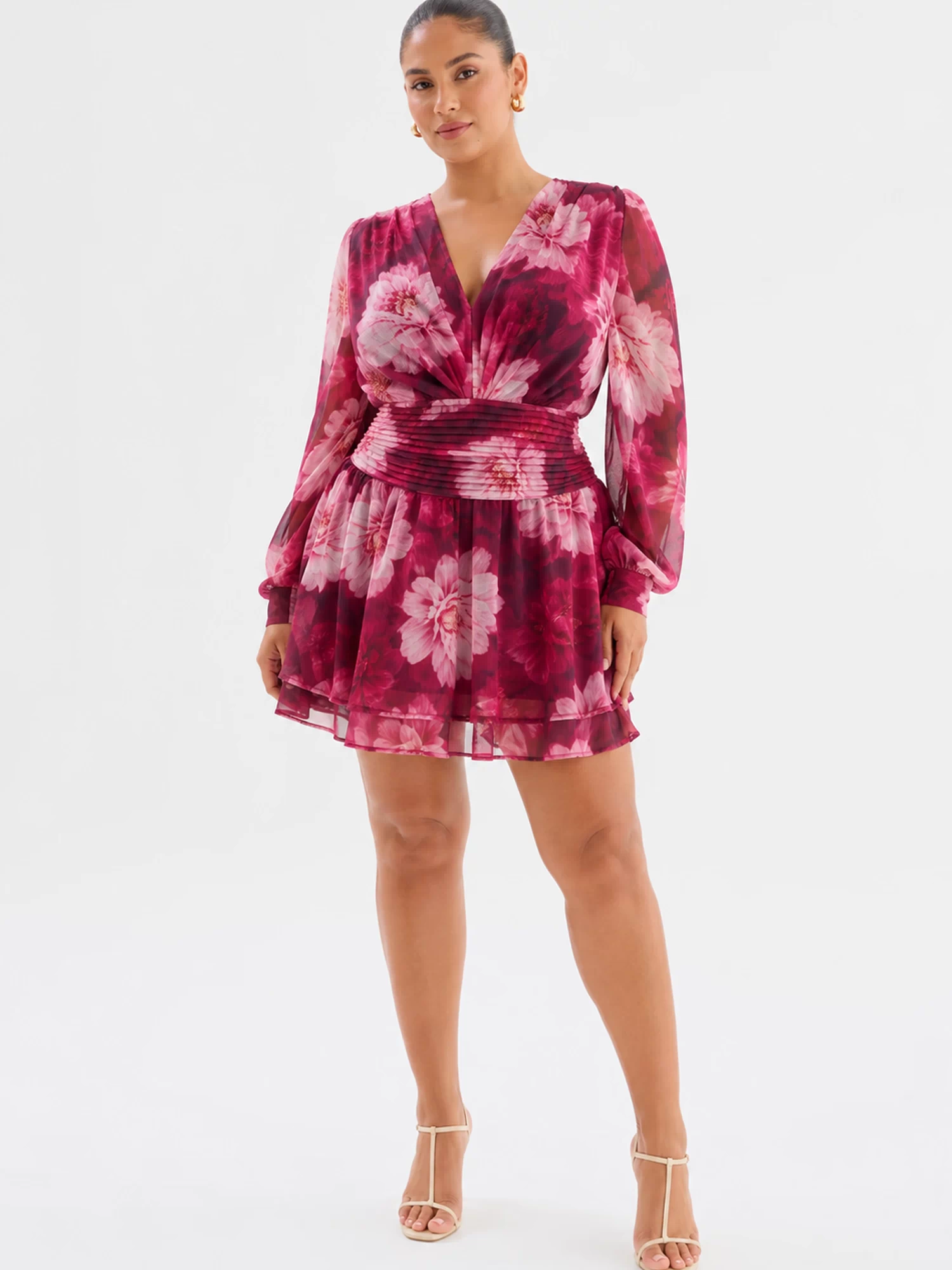 Full front view: Curve model wearing Lanarah Mini Dress in Ruby Dahlia with a plunging V-neckline, draped bodice, long sheer blouson sleeves, fitted pleated waistband and flowing mini-length silhouette.
