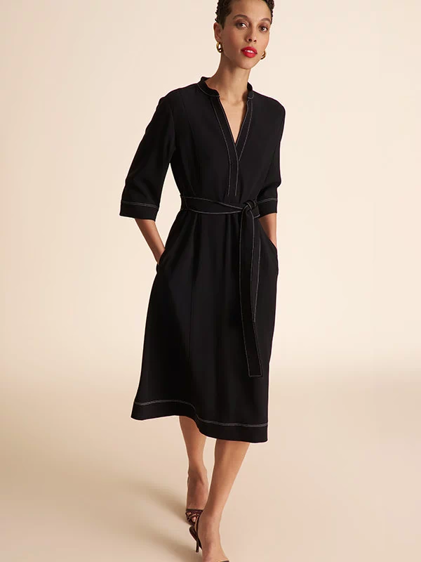 Woman wearing a black dress with a belt on a beige background | Exclude | Grid 