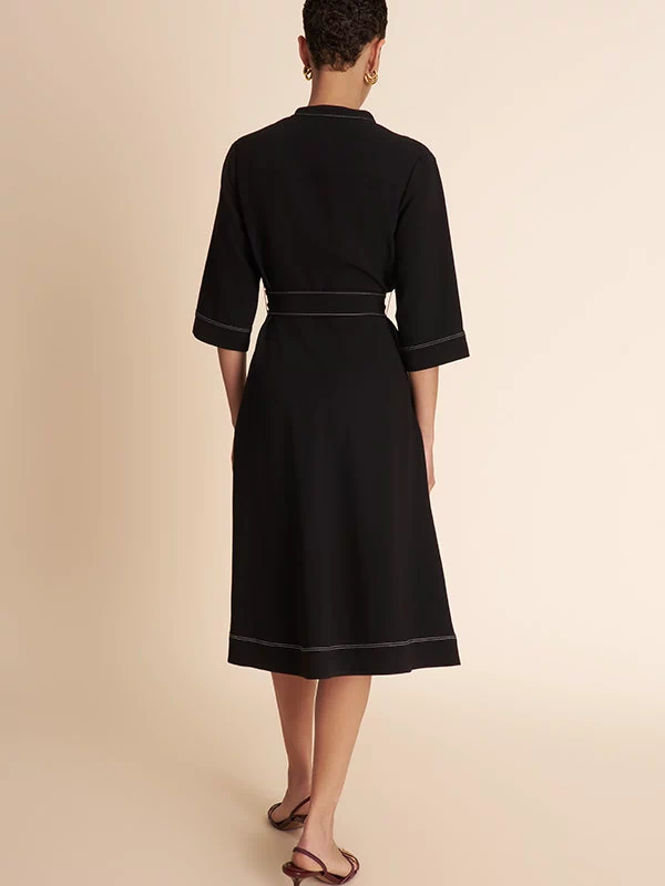 Woman wearing a black dress with a belt on a beige background | Exclude | Grid Hover