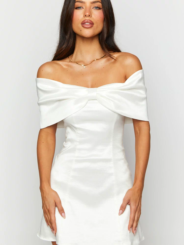 Close-up of the off-shoulder neckline and large bow detail on a white mini dress