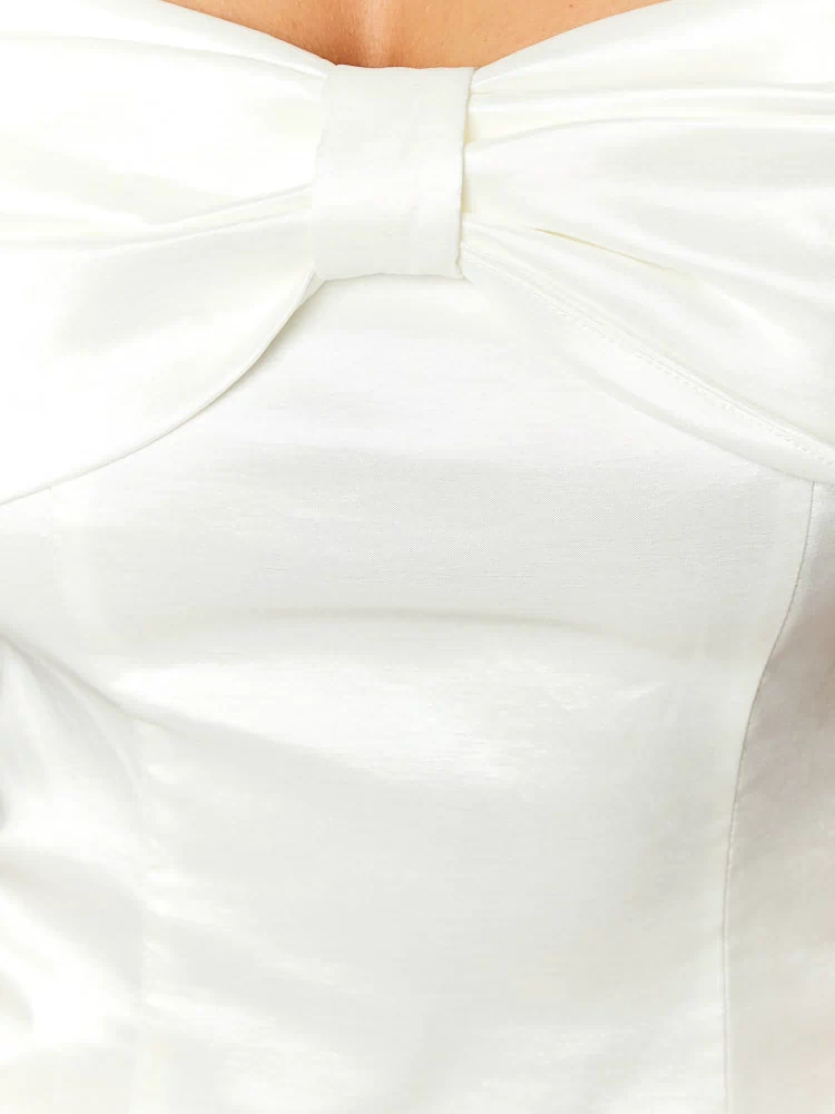 Close-up of the white satin mini dress bodice with a gathered fabric bow detail at the bust