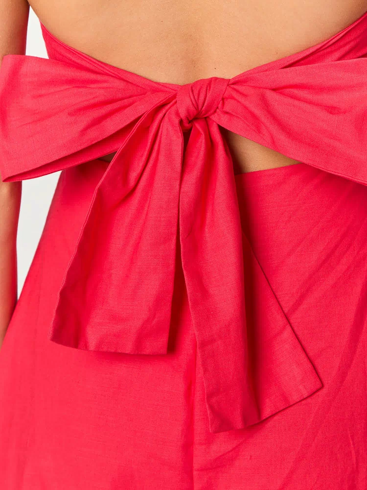 Close-up of the large red fabric bow tied at the back of the dress, with open waist cutouts
