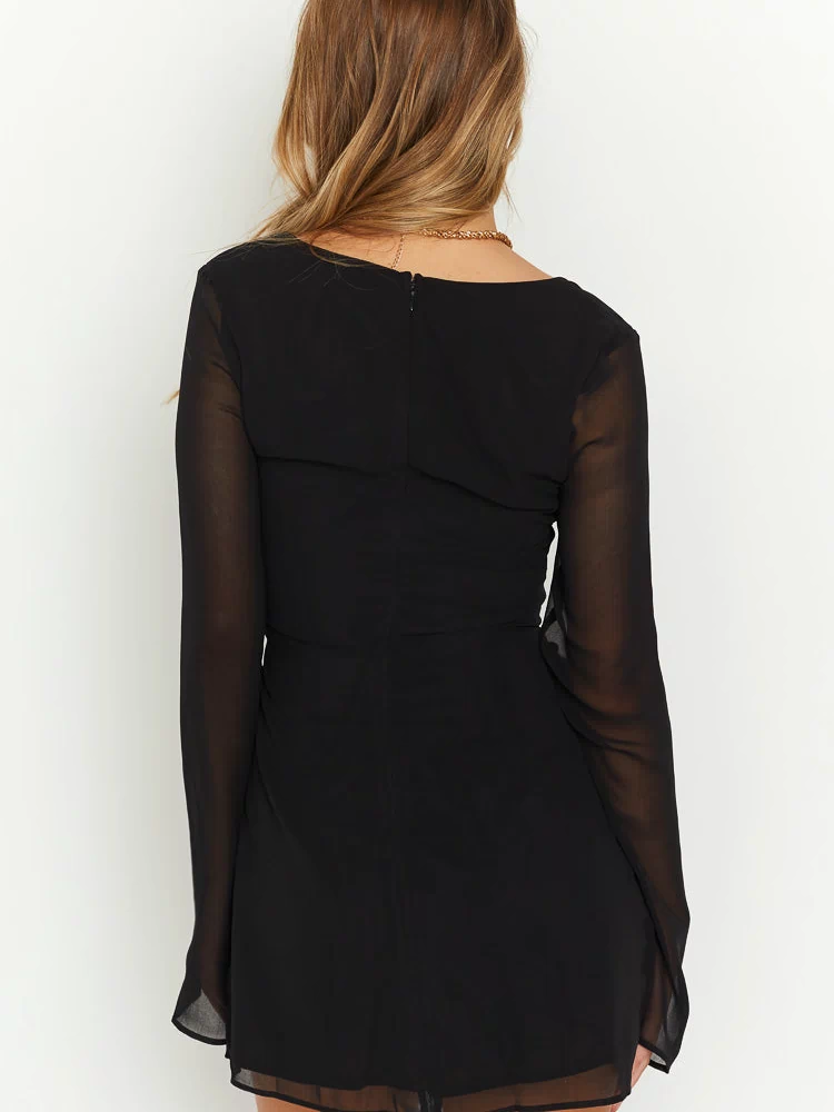 Rear view of a black long sleeve mini dress with a square back, sheer sleeves, center back zipper, and ruched detail
