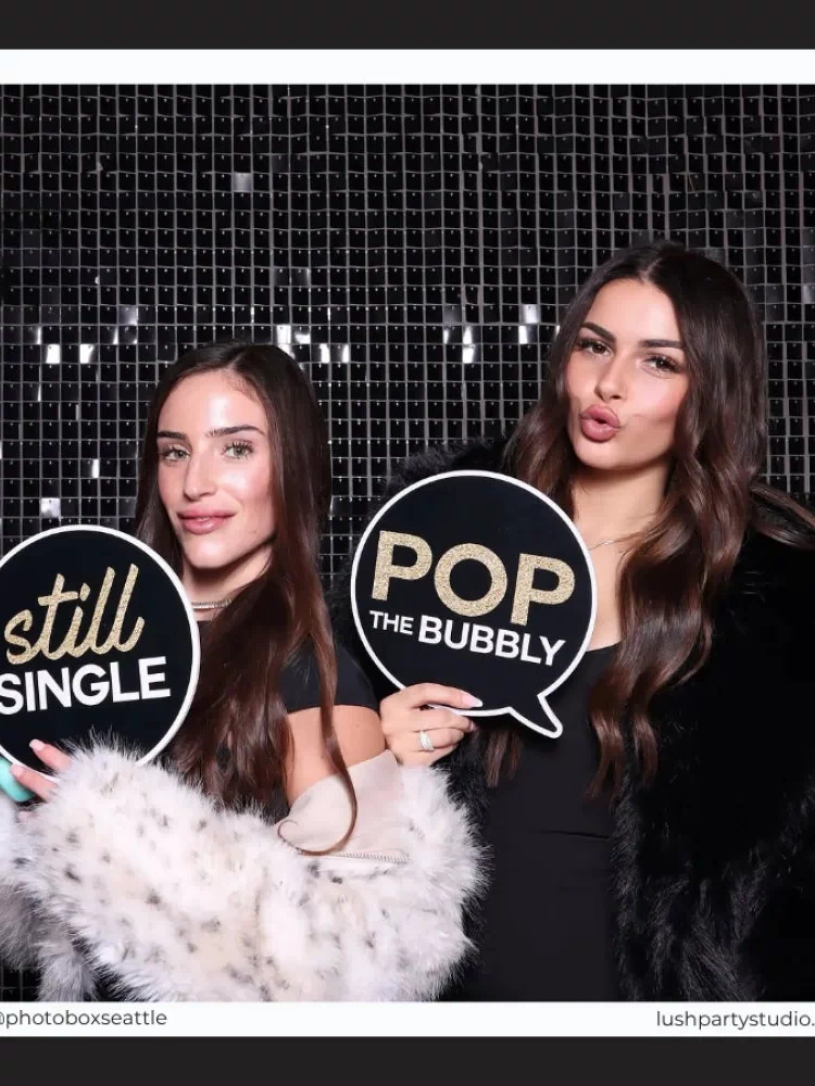 Two women holding wedding photo booth props by lush party studio

