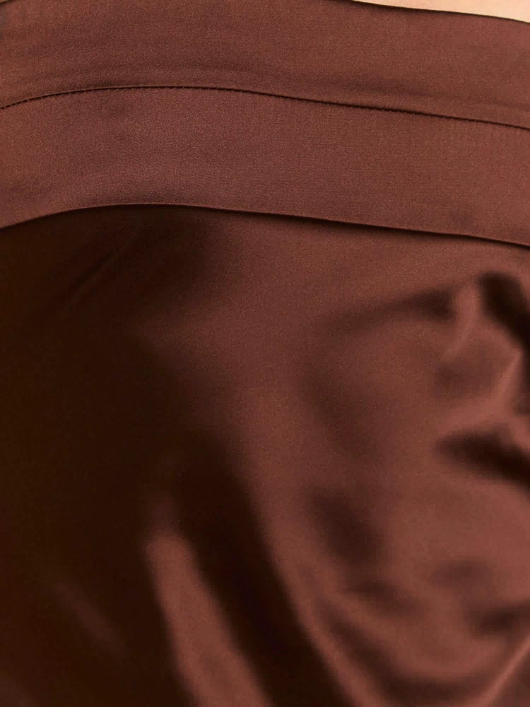 Close-up of the brown satin fabric with a visible seam detail on the maxi dress