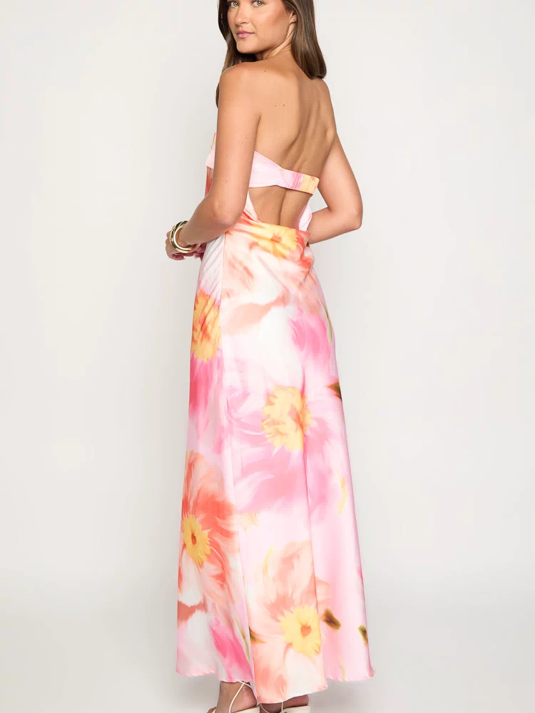 Rear view of a pink floral print maxi dress with a strapless back and waist cutout detail