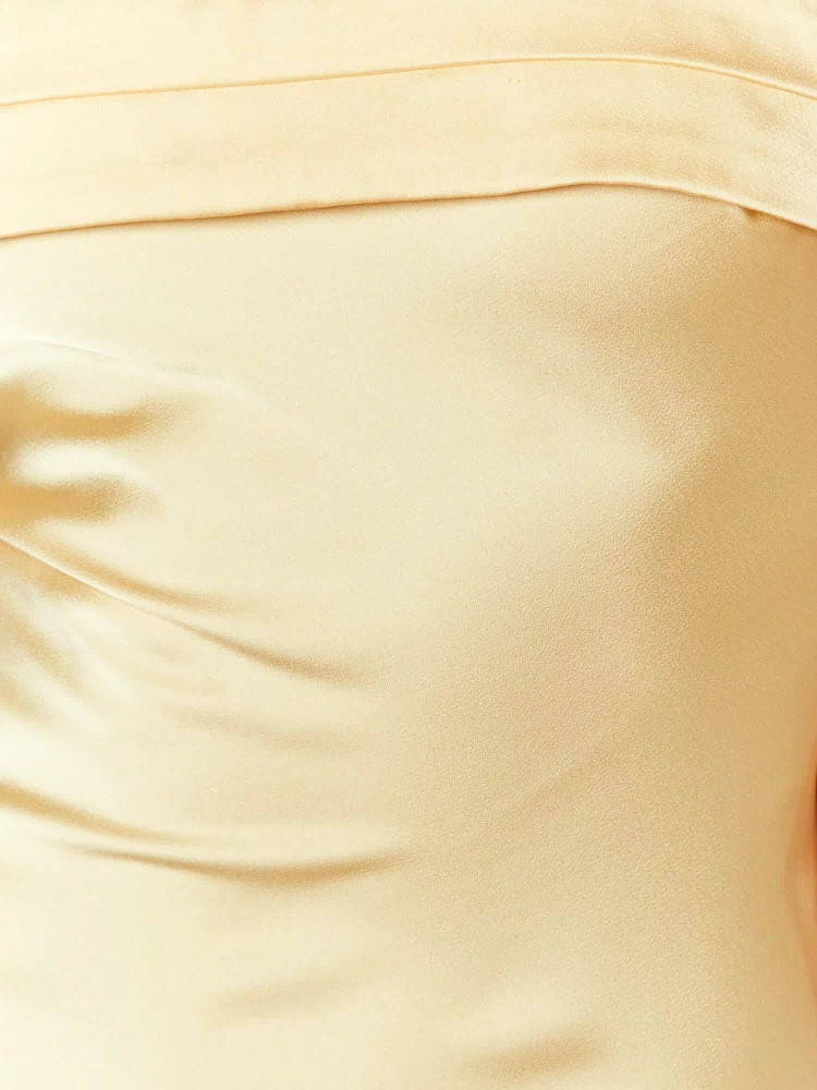 Close-up of the pale yellow fabric texture and the folded band detail at the top of the maxi dress