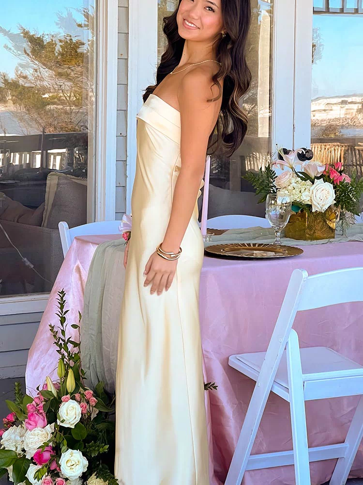 Side view of a yellow strapless satin maxi dress with a fitted bodice and flowing skirt