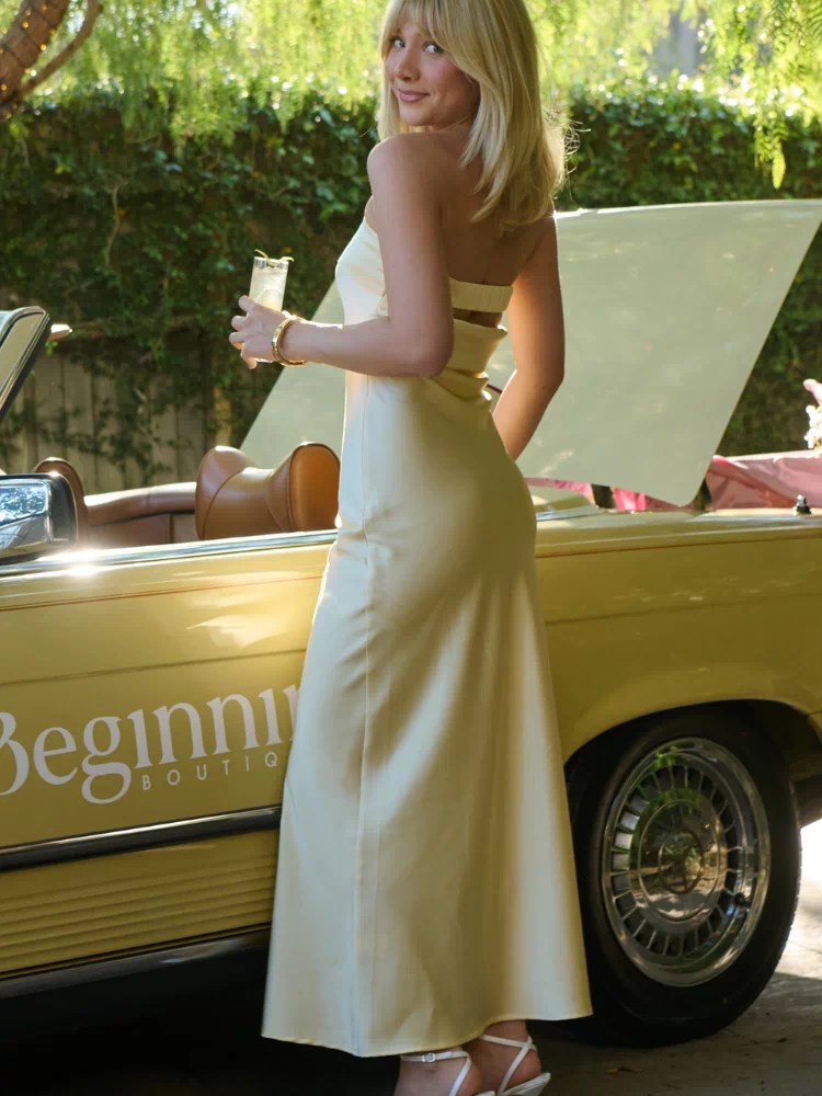 Side view of a light yellow strapless maxi dress with a cut-out back and a horizontal band