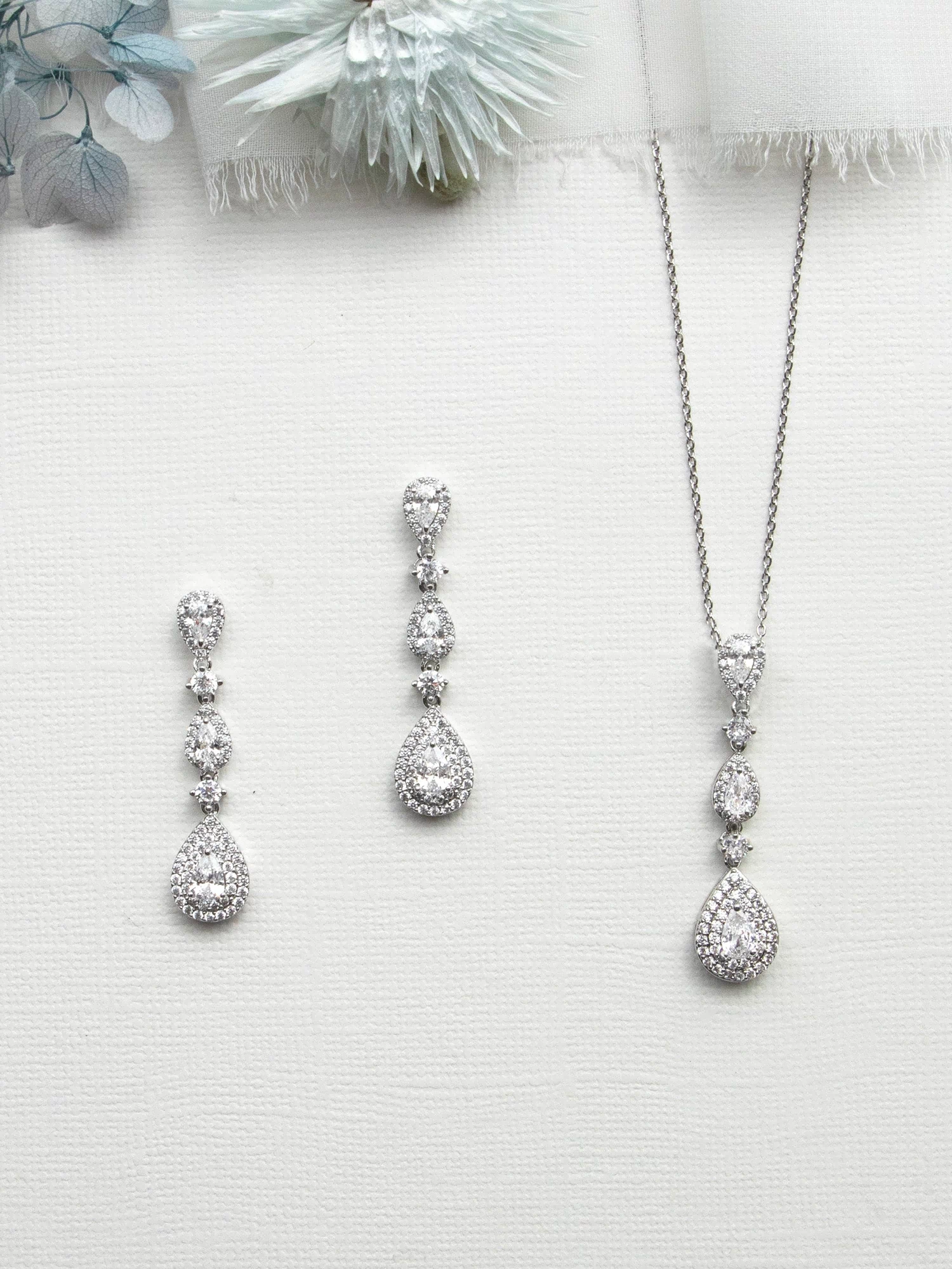 a collection of elegant jewelry pieces, including a necklace, earrings, and a pendant, all featuring a sparkling diamond design.