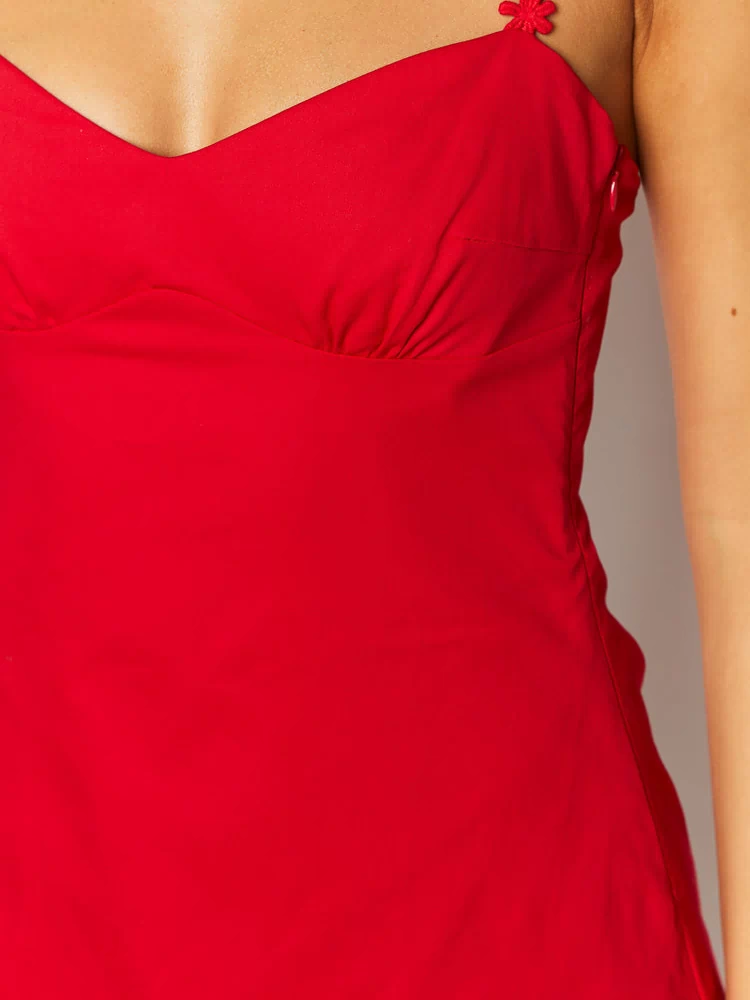 Close-up of the red mini dress showing the ruched bust, floral strap, and side zipper
